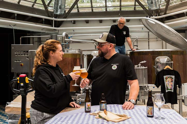 Proostmoment in brouwerij Rolduc voor de brouwketels, met speciaalbier en installaties op de achtergrond